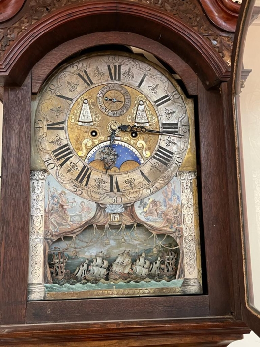 Horloge ancienne mécanique avec une scène de combat naval au bas de son cadran
